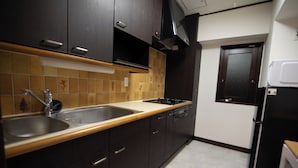 A kitchen with dark cabinets, a double sink, and a stove. - Sunmallcrest306 (Tokyo)