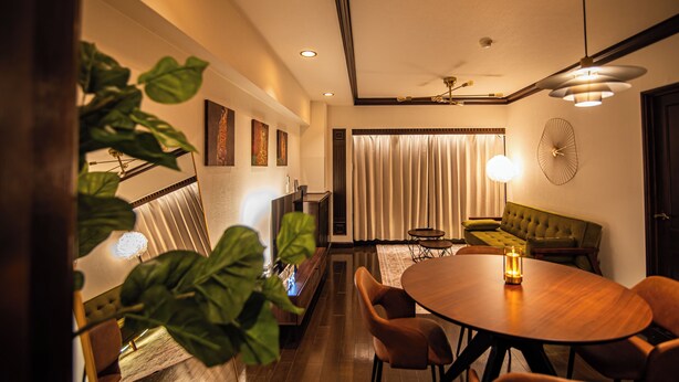 A modern dining area with a wooden table and chairs, a green sofa, and a large plant. - Sunmallcrest306 (Tokyo)