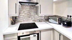 Une cuisine moderne équipée d’une cuisinière, d’un four et d’un four à micro-ondes intégrés. On y trouve également des placards et un plan de travail avec un grille-pain.