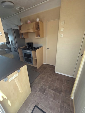 Cocina pequeña con refrigerador, estufa y armarios de madera.