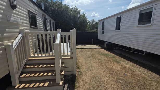 A residential area with a white house named 'The Salsa' and a paved driveway leading to a wooden staircase. - Donna 2 bed rhyl robin hood (Rhyl)