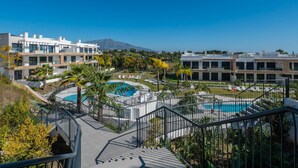 A modern resort with multiple swimming pools, a mountain in the background, and a clear blue sky. - Newly Built 2 BDRM Modern Oasis w Gym & Pool (Estepona)