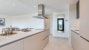 A modern kitchen with a central island, built-in appliances, and a view to the outside. - Newly Built 2 BDRM Modern Oasis w Gym & Pool (Estepona)