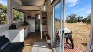Une petite cuisine équipée d’un four à micro-ondes, d’un évier et d’une fenêtre donnant sur un paysage aride.
