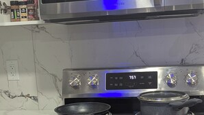 A kitchen with a stainless steel microwave, oven, and two pots on the stove.