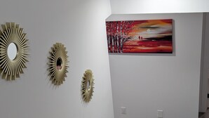 A modern interior with white walls, a staircase, and three decorative wall mirrors.