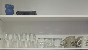 A kitchen with a marble backsplash, a stainless steel sink, and a dish soap bottle.