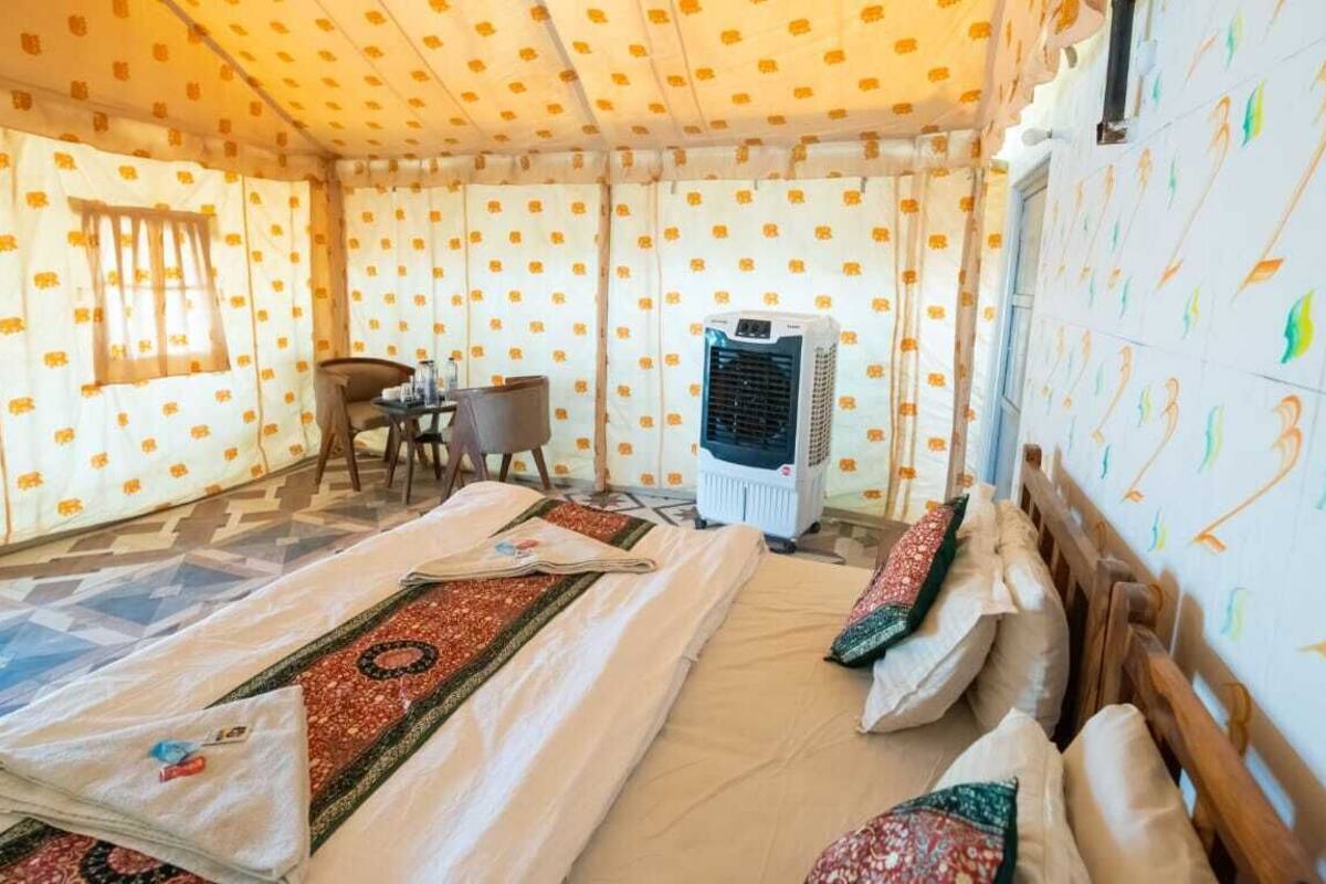 Una habitación con cama, una silla, una mesa y un equipo de aire acondicionado.