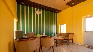 A room with a green and white striped wall, a wooden ceiling, a desk with a laptop, two chairs, and a small table with a bottle. - ACE Desert Resort (Jaisalmer)