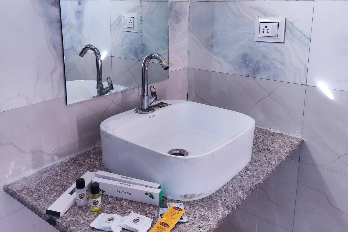 Un baño con lavamanos blanco, espejo y encimera de granito.