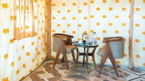 A corner room with a patterned curtain, a small table with chairs, and a tiled floor. - ACE Desert Resort (Jaisalmer)