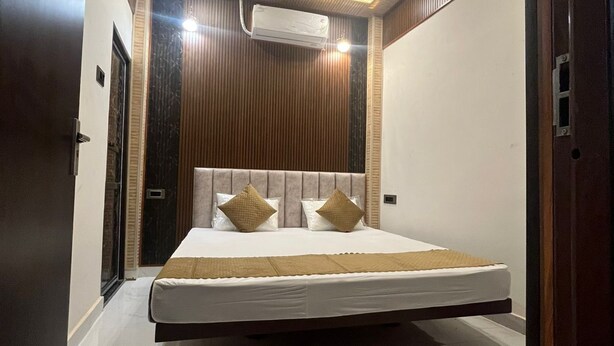 A modern bedroom with a bed, ceiling fan, and air conditioning unit. - Om Nilay Paying Guest House By GRB (Varanasi)