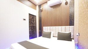 A modern bedroom with a large bed, wooden paneling, and a marble accent wall. - Om Nilay Paying Guest House By GRB (Varanasi)
