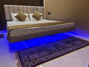 Ein Bett mit Kopfteil, ein gemustertes Teppich und ein blau beleuchteter Boden.