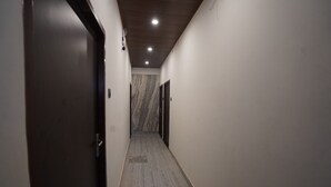 A hallway with a wooden ceiling, marble walls, and a carpeted floor. - Om Nilay Paying Guest House By GRB (Varanasi)