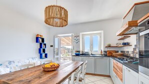 Une cuisine moderne avec une table en bois, des armoires blanches et un luminaire suspendu.