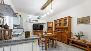 Una cocina moderna con encimeras de granito, armarios de madera y un comedor con mesa y sillas.