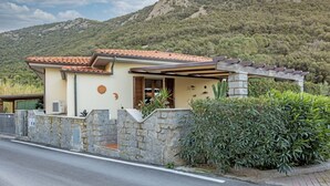 Una villa de estilo mediterráneo con fachada de piedra, tejas de arcilla y un muro de piedra con una verja.