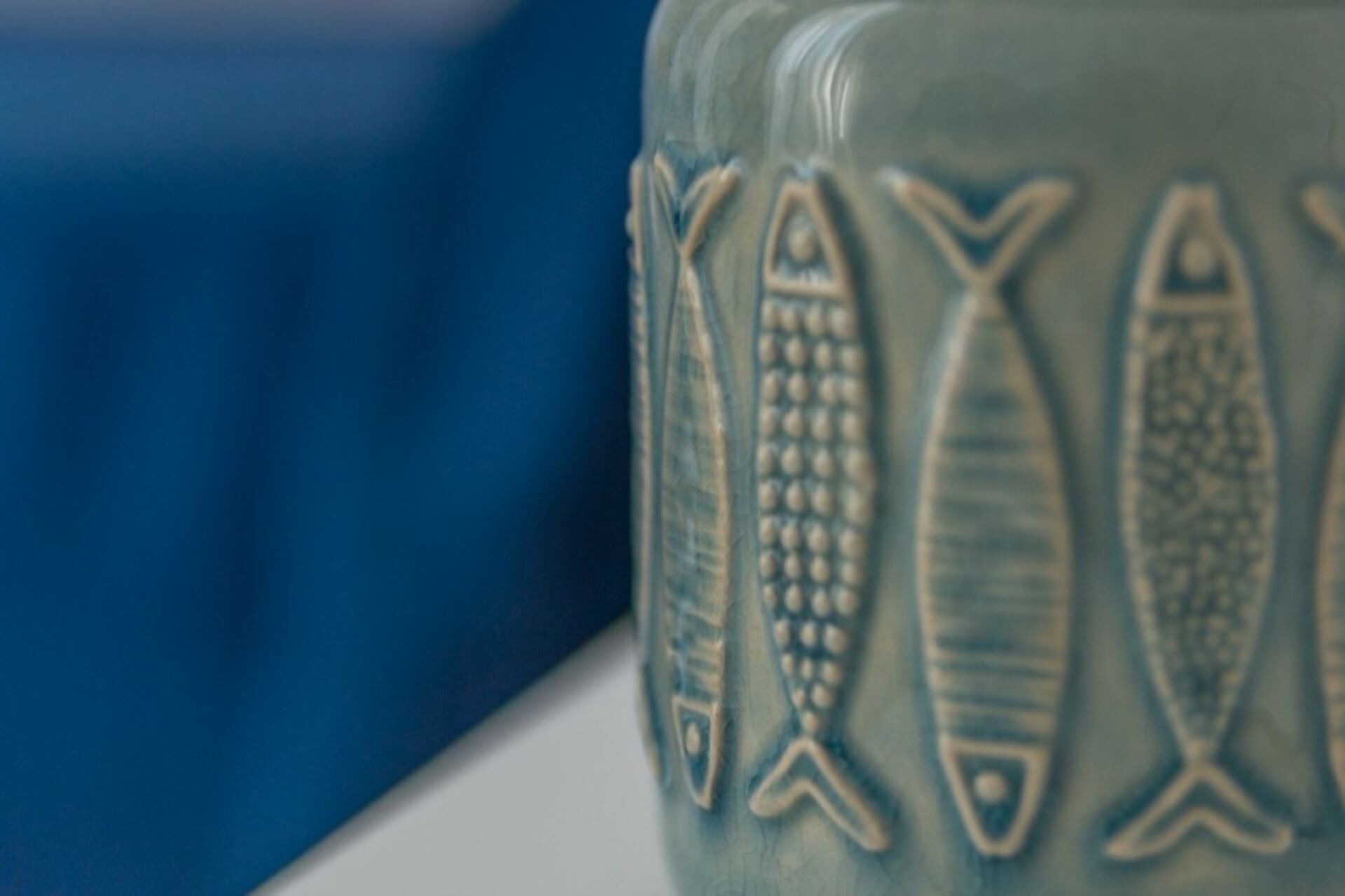 A close-up of a ceramic mug with fish designs.