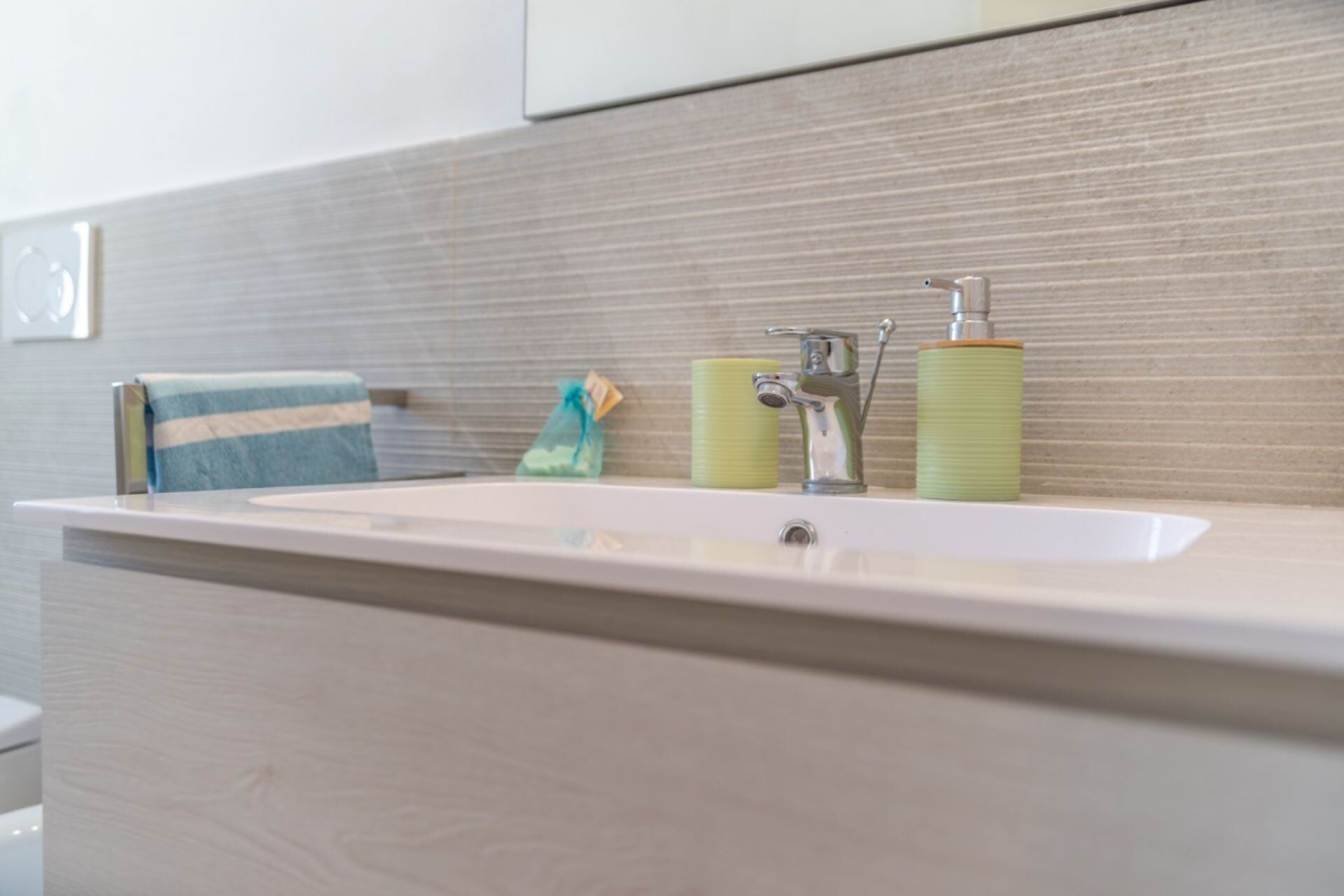Een badkamer met een witte wastafel, een handdoek en twee groene zeepdispensers.