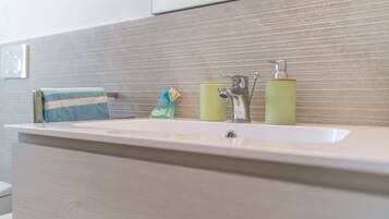 Een badkamer met een witte wastafel, een handdoek en twee groene zeepdispensers.