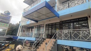 A building with a blue and white facade, a sign for 'Palawan United Music', and a staircase leading to the entrance.