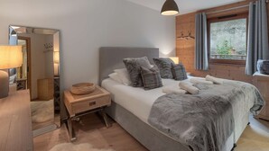 Un dormitorio con cama, mesita de noche, lámpara y una ventana con cortinas.