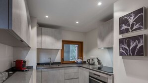 Cocina moderna con armarios grises, horno integrado y ventana con vistas a zonas verdes.
