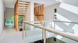 Een modern interieur met een glazen balustrade, een wand van houten latten en een trap naar een buitengebied.