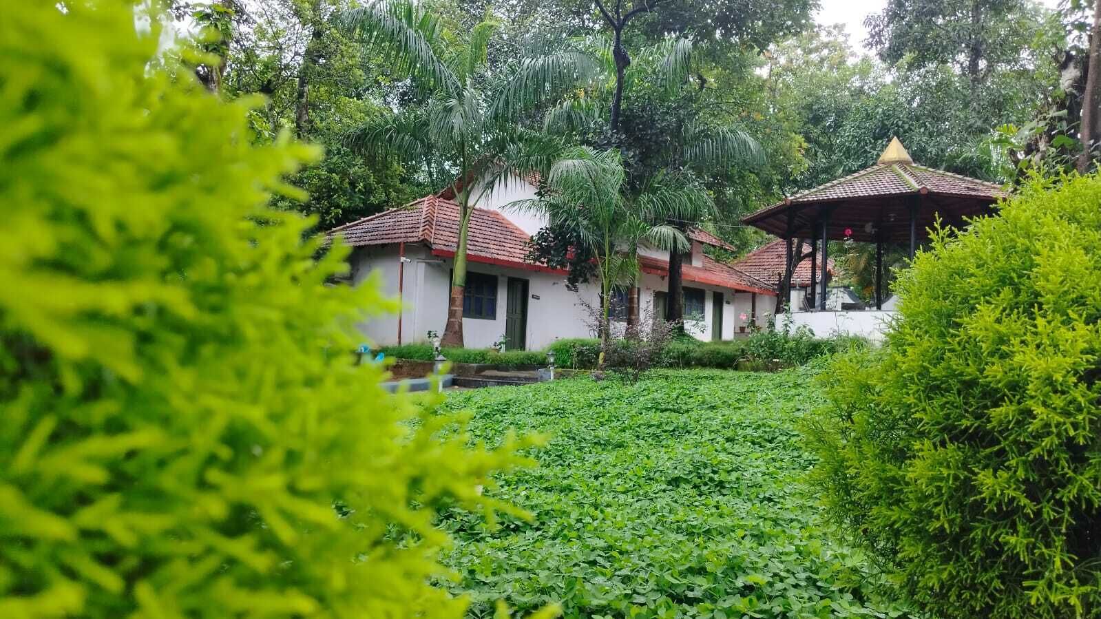 Un edificio tradicional con tejado de tejas rojas, rodeado de exuberante vegetación y un estanque.