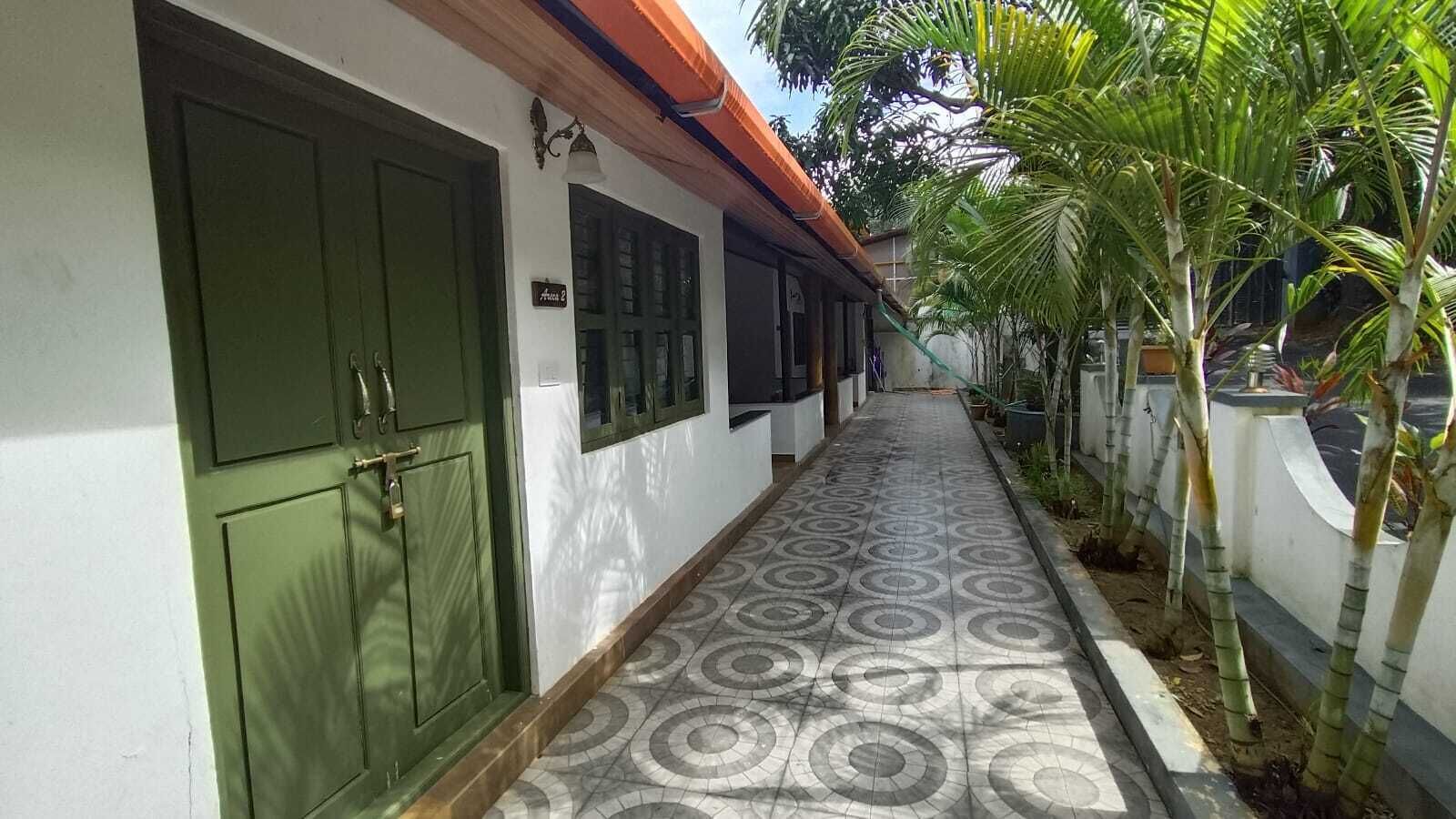 A corridor with patterned flooring, green doors, and a small sign.