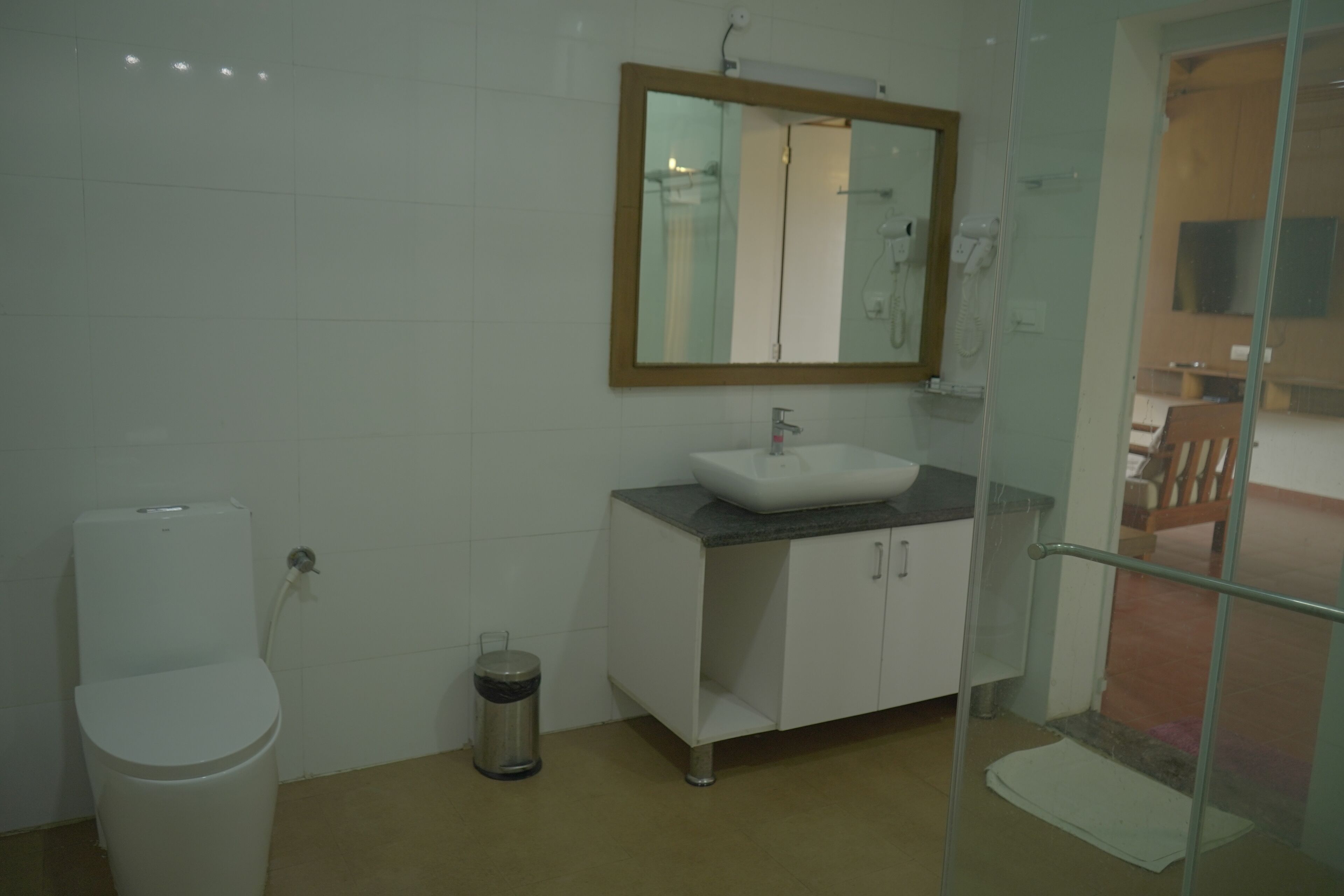 A bathroom with a white toilet, a sink with a mirror above it, and a trash bin.