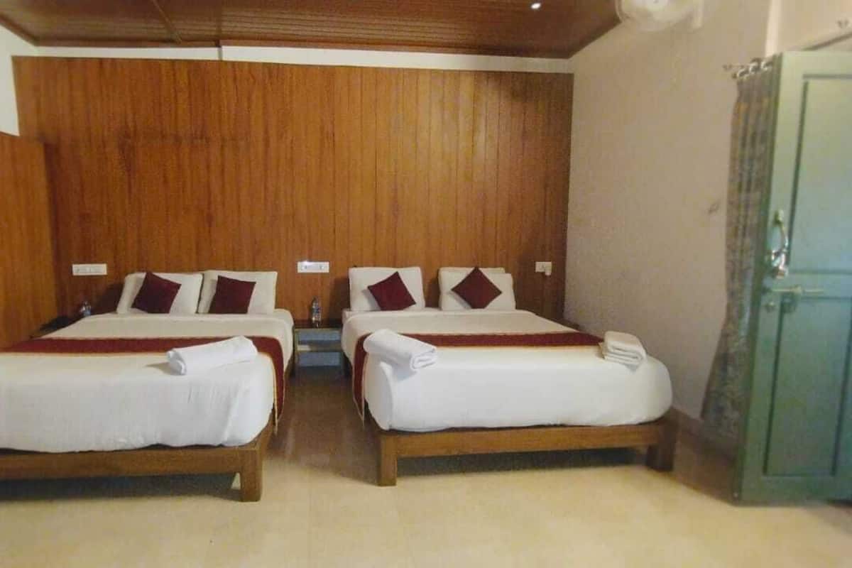 A room with two beds, wooden headboards, and a green door.