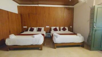 A room with two beds, wooden headboards, and a green door.