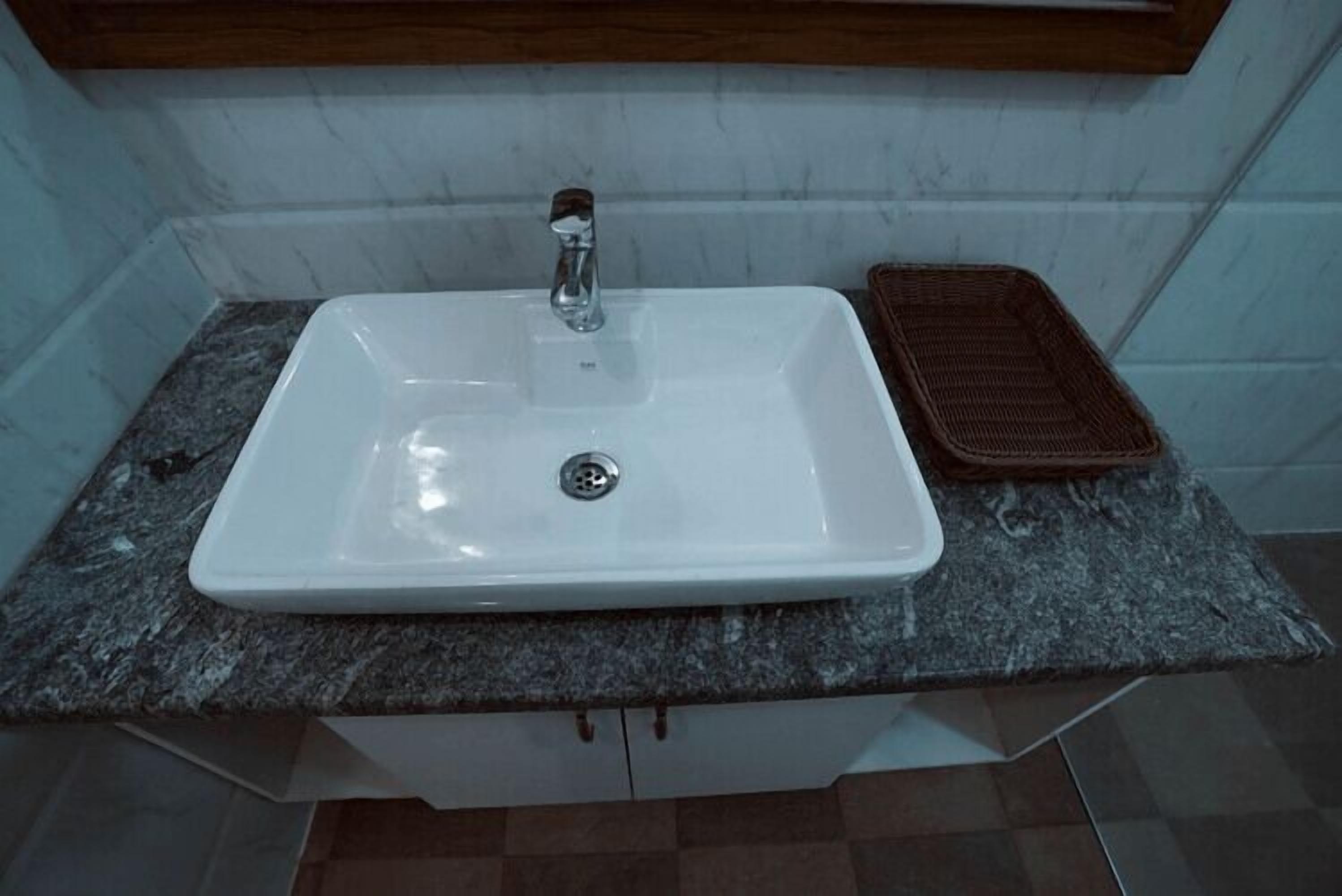 A white rectangular sink with a single faucet, set on a granite countertop.