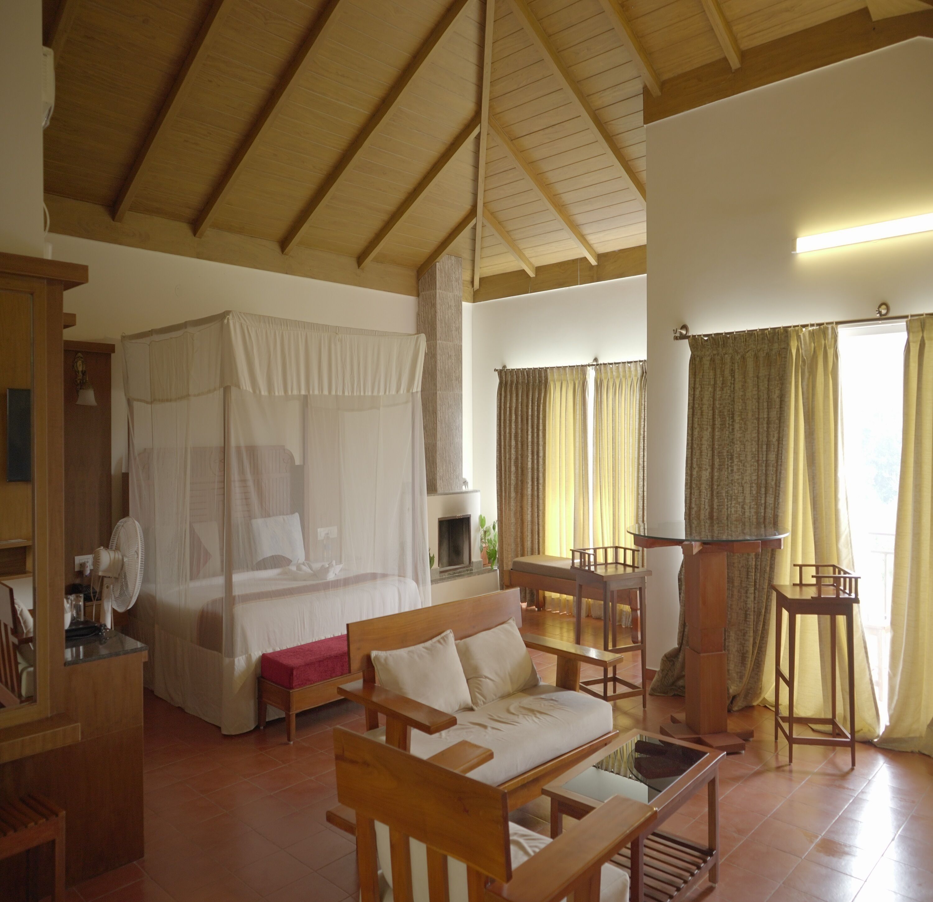 Un'ampia stanza con soffitto in legno, un letto a baldacchino, un divano, un tavolino e una sedia.