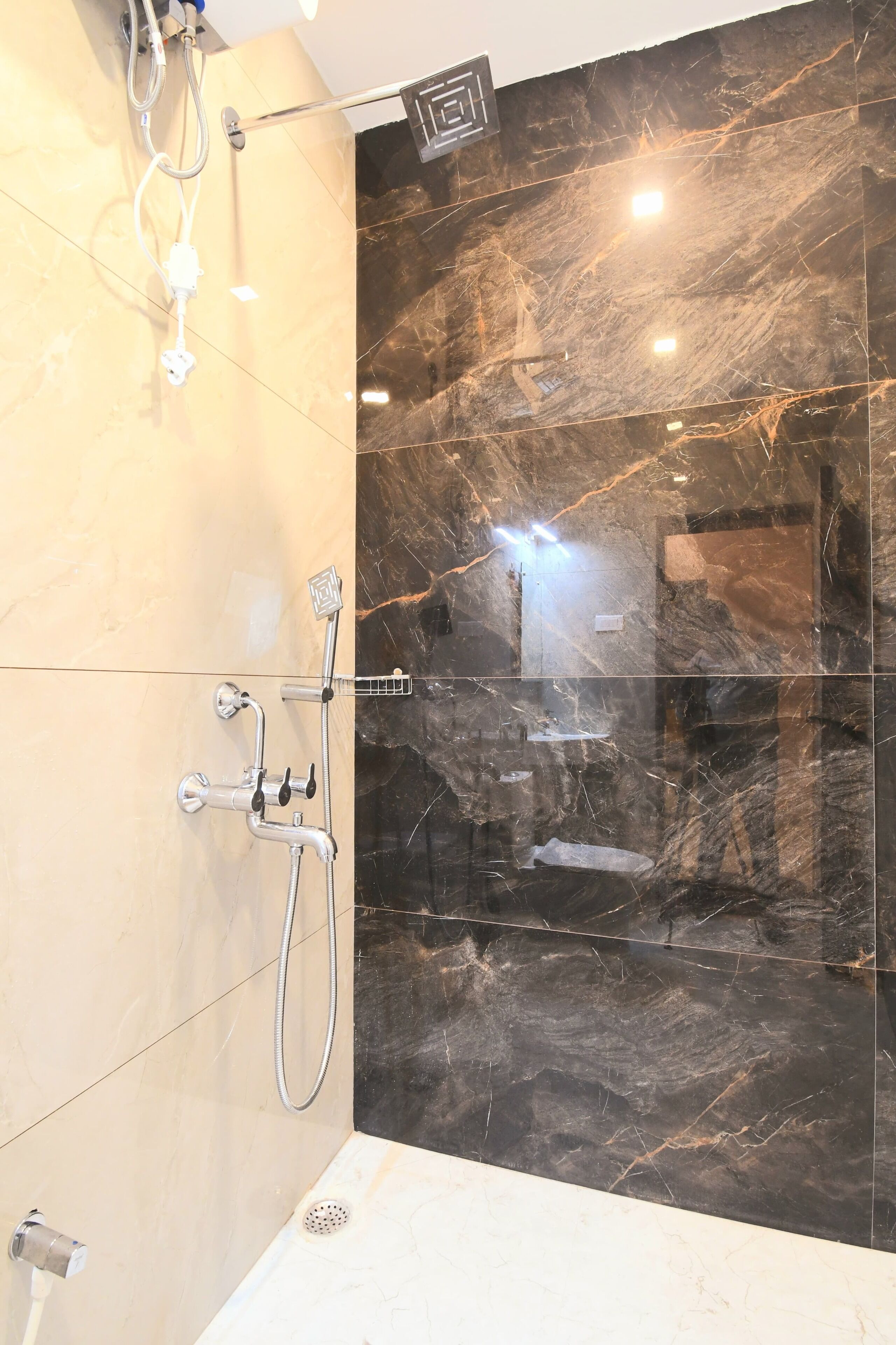 Een moderne badkamer met een douchewand van marmer, een handdouche en een wandmengkraan.