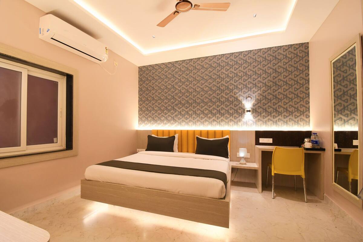A modern hotel room with a bed, a desk, a chair, and a ceiling fan.