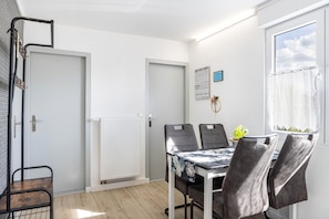Uma área de refeições com mesa, cadeiras, radiador e janela com cortinas.