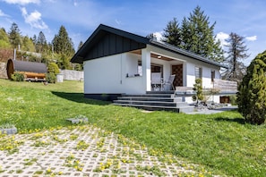 Una casa moderna con facciata bianca, tetto nero e un portico con gradini che conducono all'ingresso.