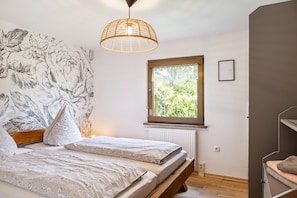 Una camera da letto con un letto, una finestra, un termosifone e una parete decorata con un motivo floreale.
