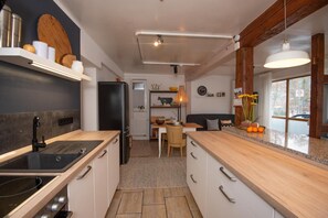 Moderni keittiö, jossa on musta jääkaappi, puutasot ja ruokailutila, jossa on pöytä ja tuolit.