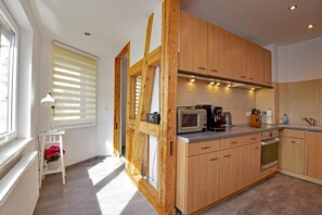 Eine moderne Küche mit Holzausstattung, einer Mikrowelle, einem Wasserkocher und einem kleinen Tisch mit einer Lampe.