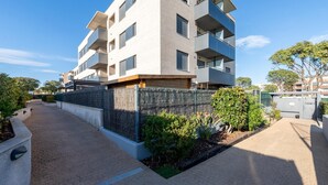 A modern multi-story residential building with balconies, a gated entrance, and a paved pathway. - Apartment with pool and paddle tennis 500m beach (Torredembarra)