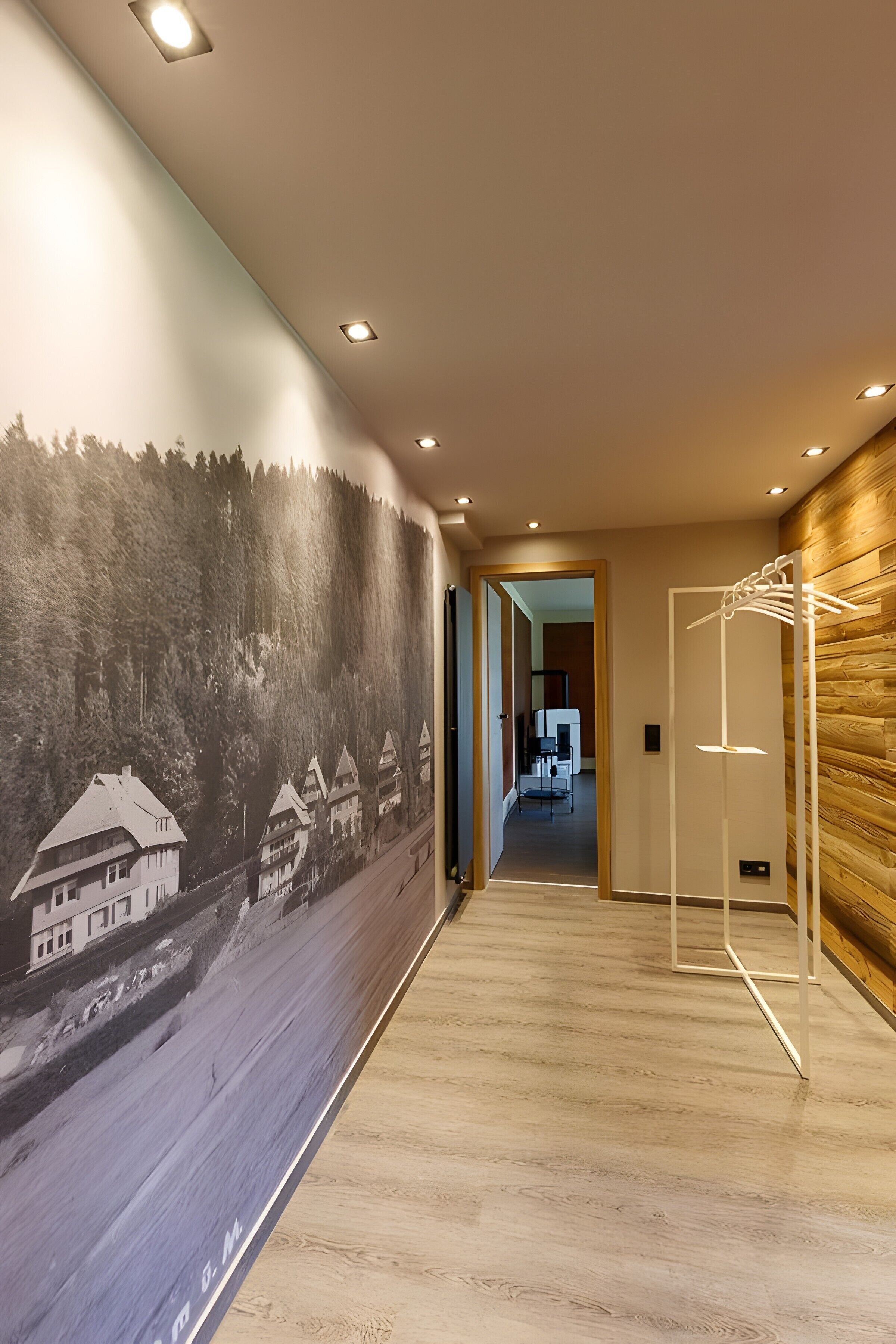 A hallway with a mural of a forested landscape, wooden paneling, and a modern light fixture.