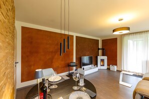 Un salon moderne avec une cheminée, un téléviseur à écran plat, une table à manger avec des verres à vin et un canapé.
