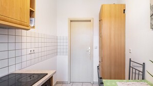 A small kitchen with a stove, cabinets, and a door. - Apartment 'Auf Zeit' with Wi-Fi (Leipzig)
