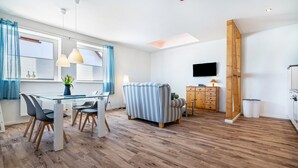 A modern room with a dining table, chairs, a sofa, a TV, and a wooden cabinet. - Apartment 'Fewo 1' with Private Terrace and Wi-Fi (Klink)