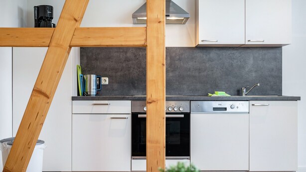 A modern kitchen with white cabinets, a stainless steel range, and a built-in dishwasher. - Apartment 'Fewo 1' with Private Terrace and Wi-Fi (Klink)
