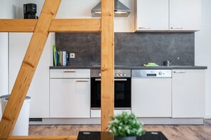 Une cuisine moderne avec des armoires blanches, une cuisinière en acier inoxydable et un lave-vaisselle intégré.